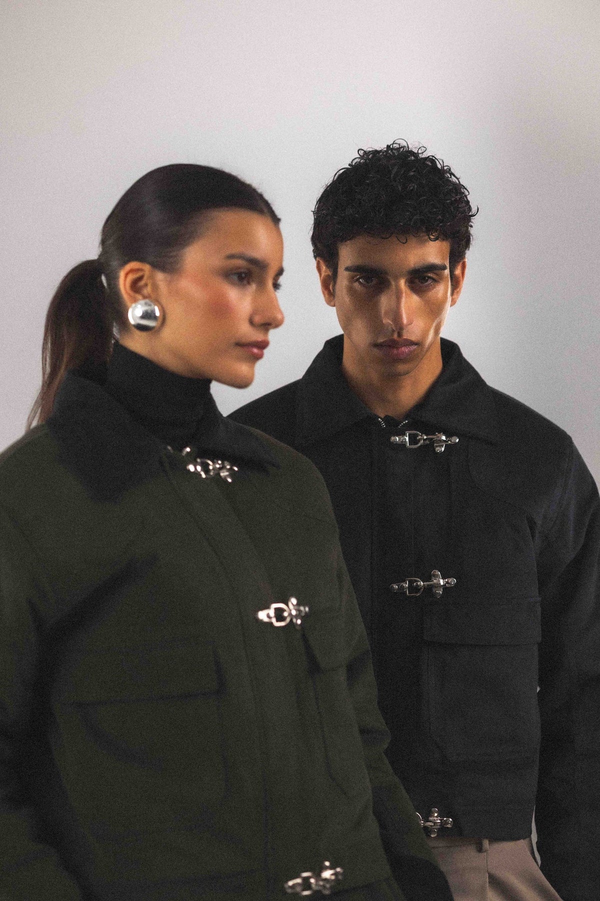 Blouson court Adam Vert, silhouette complète, look styliste, avec ses trois boucles pompiers qui se ferment au-dessus du zip