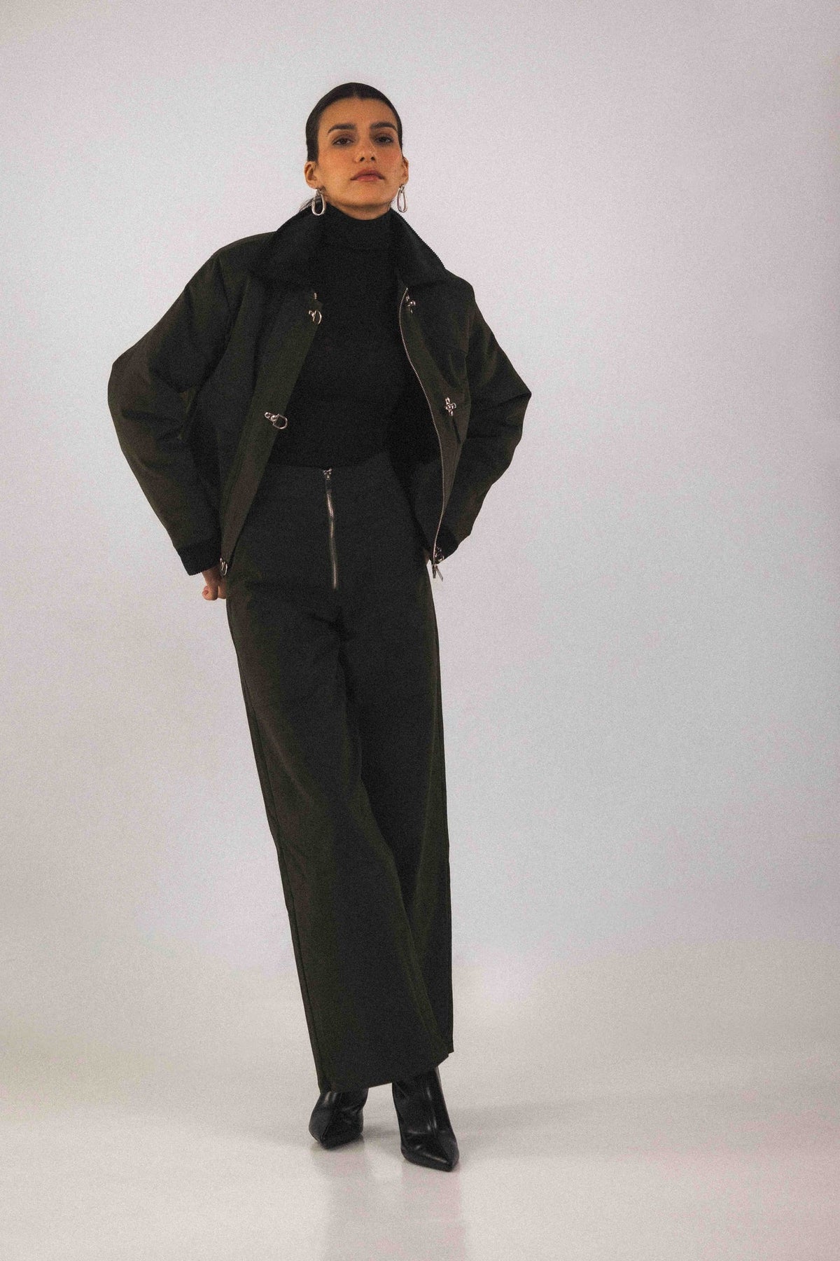 Blouson court Adam Vert, porté, vue de profil, avec ses trois boucles pompiers qui se ferment au-dessus du zip, coupe unisexe pensée pour toutes les silhouettes