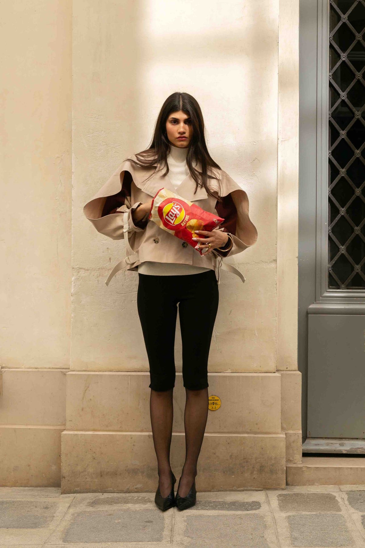 Trench court Anita Beige, porté en mouvement, associée à des sangles ajustables aux poignets et sur les côtés