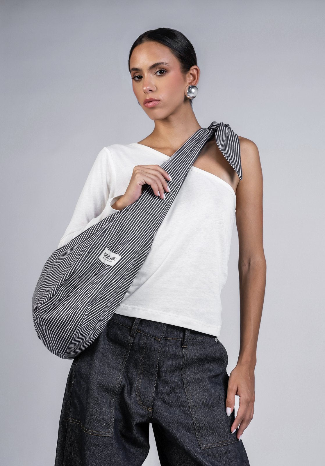 Sac à nouer en denim rayé bleu/blanc Sasha, premier regard, portée en extérieur, offre plusieurs façons de le porter : en bandoulière classique ou à l'épaule