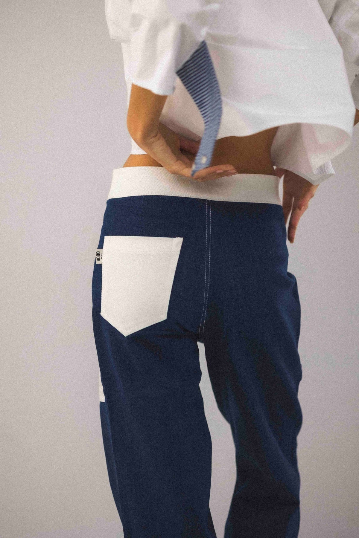 Pantalon Bourgogne, porté en mouvement, il se distingue par ses poches plaquées blanches et son zip argenté avec tirette en anneau